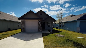 A single-story house with a garage, a front yard, and a clear sky.