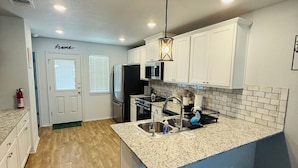 A modern kitchen with white cabinets, a granite countertop, and a built-in island with a sink.
