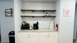 A kitchen with white cabinets, a granite countertop, a coffee maker, and a microwave.