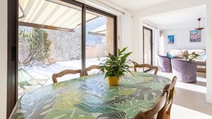 A dining area with a table, chairs, a potted plant, and a view of the outdoors. - Au fil du Réguinier – Seasonal Rental Cottage (Briançon)