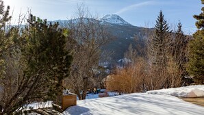 A snowy landscape with a mountain in the background, trees, and a wooden structure. - Au fil du Réguinier – Seasonal Rental Cottage (Briançon)