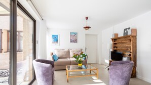 A living room with a sofa, two armchairs, a coffee table, a TV, and a wooden bookshelf. - Au fil du Réguinier – Seasonal Rental Cottage (Briançon)
