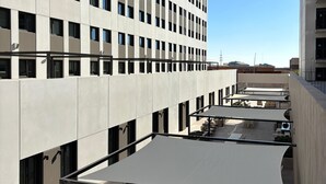 A modern building with a rooftop patio featuring outdoor seating and a large canopy. - Yugo Terrassa (Terrassa)