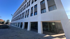 A modern building with a flat facade, multiple windows, and a paved entrance area. - Yugo Terrassa (Terrassa)
