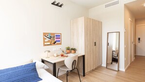 A modern bedroom with a bed, a desk, and a chair. There is a wardrobe, a mirror, and a small plant on the desk. - Yugo Terrassa (Terrassa)