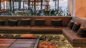 A modern interior with a large window, a woven ceiling light, a sofa with patterned cushions, and a geometric floor design. - Wake up to turquoise waters at Isla Bliss 🌴 — a luxury 3-bedroom oceanfront condo just minutes from Isla Mujeres’ best dining and beaches. Enjoy a 90" Smart TV, stunning views, fast WiFi, and easy self-check-in for the perfect island escape. 🌊✨ (Isla Mujeres)