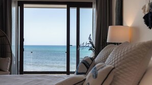 A hotel room with a bed, a view of the ocean, and a sliding glass door. - Wake up to turquoise waters at Isla Bliss 🌴 — a luxury 3-bedroom oceanfront condo just minutes from Isla Mujeres’ best dining and beaches. Enjoy a 90" Smart TV, stunning views, fast WiFi, and easy self-check-in for the perfect island escape. 🌊✨ (Isla Mujeres)