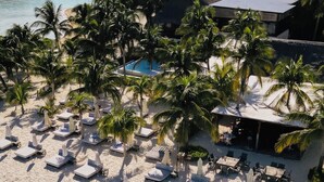 A beach resort with sun loungers, a pool, and palm trees. - Wake up to turquoise waters at Isla Bliss 🌴 — a luxury 3-bedroom oceanfront condo just minutes from Isla Mujeres’ best dining and beaches. Enjoy a 90" Smart TV, stunning views, fast WiFi, and easy self-check-in for the perfect island escape. 🌊✨ (Isla Mujeres)
