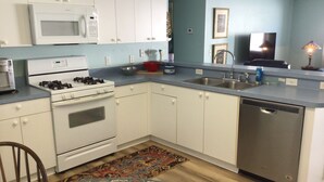 A compact kitchen with white cabinets, a microwave, stove, sink, and dishwasher. - Live the Villages lifestyle in  this 2 bedroom beauty (The Villages)