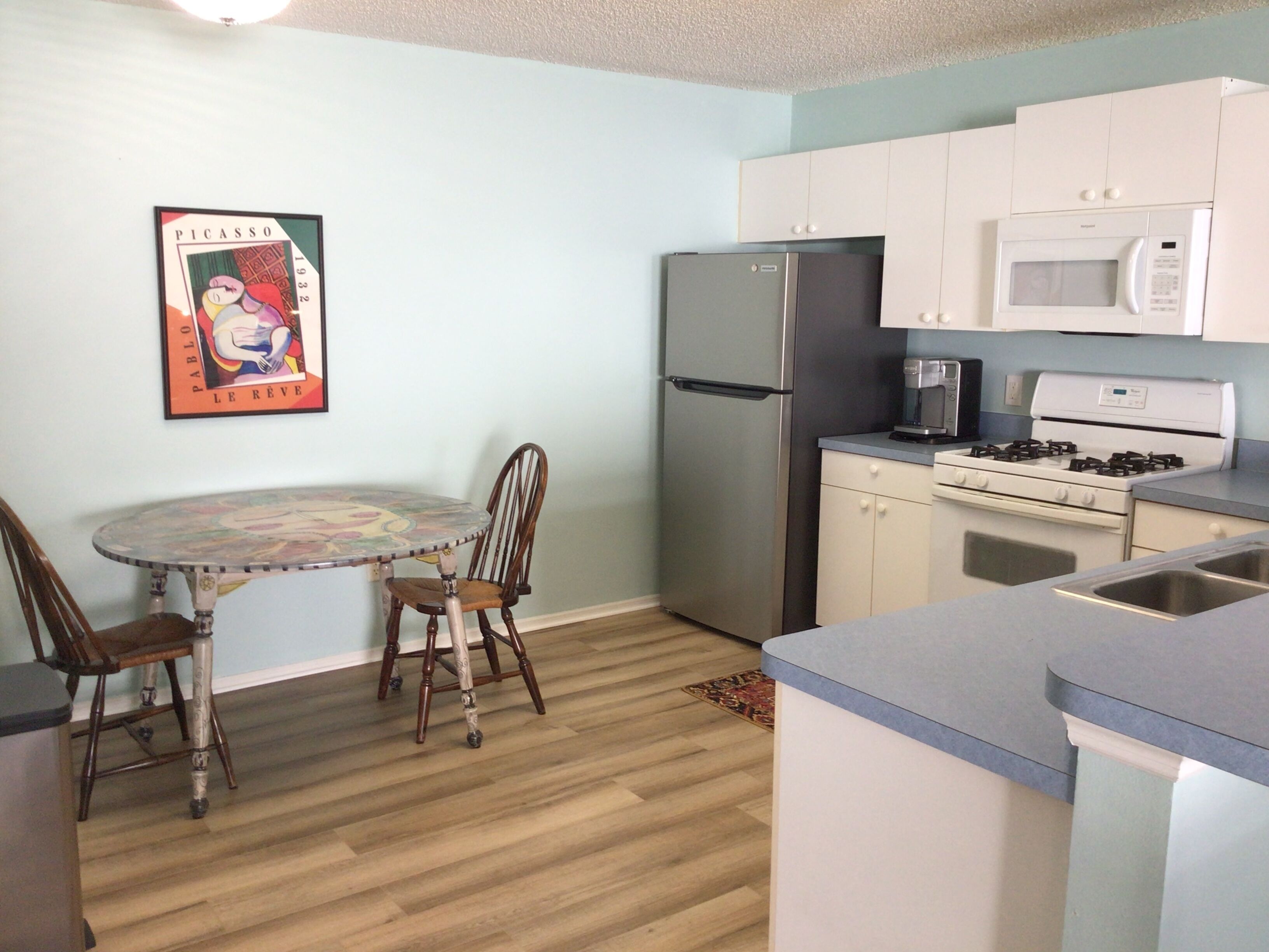 A compact kitchen with a refrigerator, microwave, stove, and a dining table with chairs.