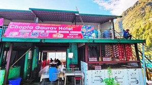 Hotelli nimeltä ”Chopta Gaurav Hotel”, jonka kyltissä mainostetaan aamiaista, lounasta, illallista ja huoneita.