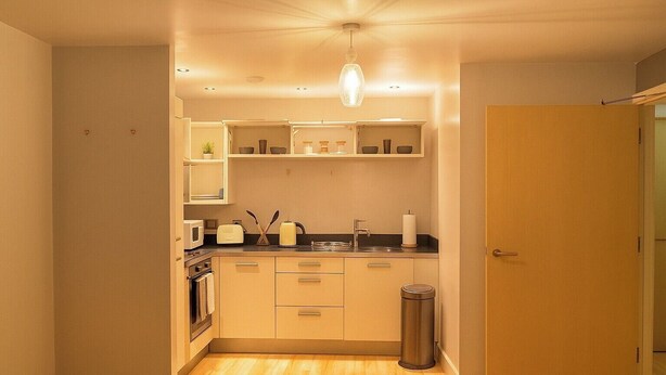 A compact kitchen with wooden cabinets, a stainless steel sink, and a trash can. - Apt - Sleeps 2 - Parking - Station Close (Manchester)