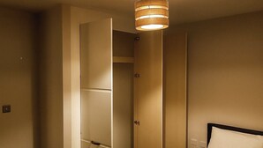 A hotel room with a bed, a wardrobe, and a hanging light fixture. - Apt - Sleeps 2 - Parking - Station Close (Manchester)
