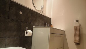 A bathroom with a toilet, a sink, and a towel hanging on the wall. - Apt - Sleeps 2 - Parking - Station Close (Manchester)
