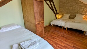 Un dormitorio con dos camas, vigas de madera, pared de piedra y suelo de madera.