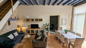 Una sala de estar acogedora con sofá, mesa de centro, televisor y comedor con mesa y sillas.