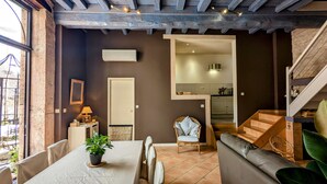 Un interior acogedor con una zona de comedor, un área de estar y una cocina visible a través de un umbral abierto.