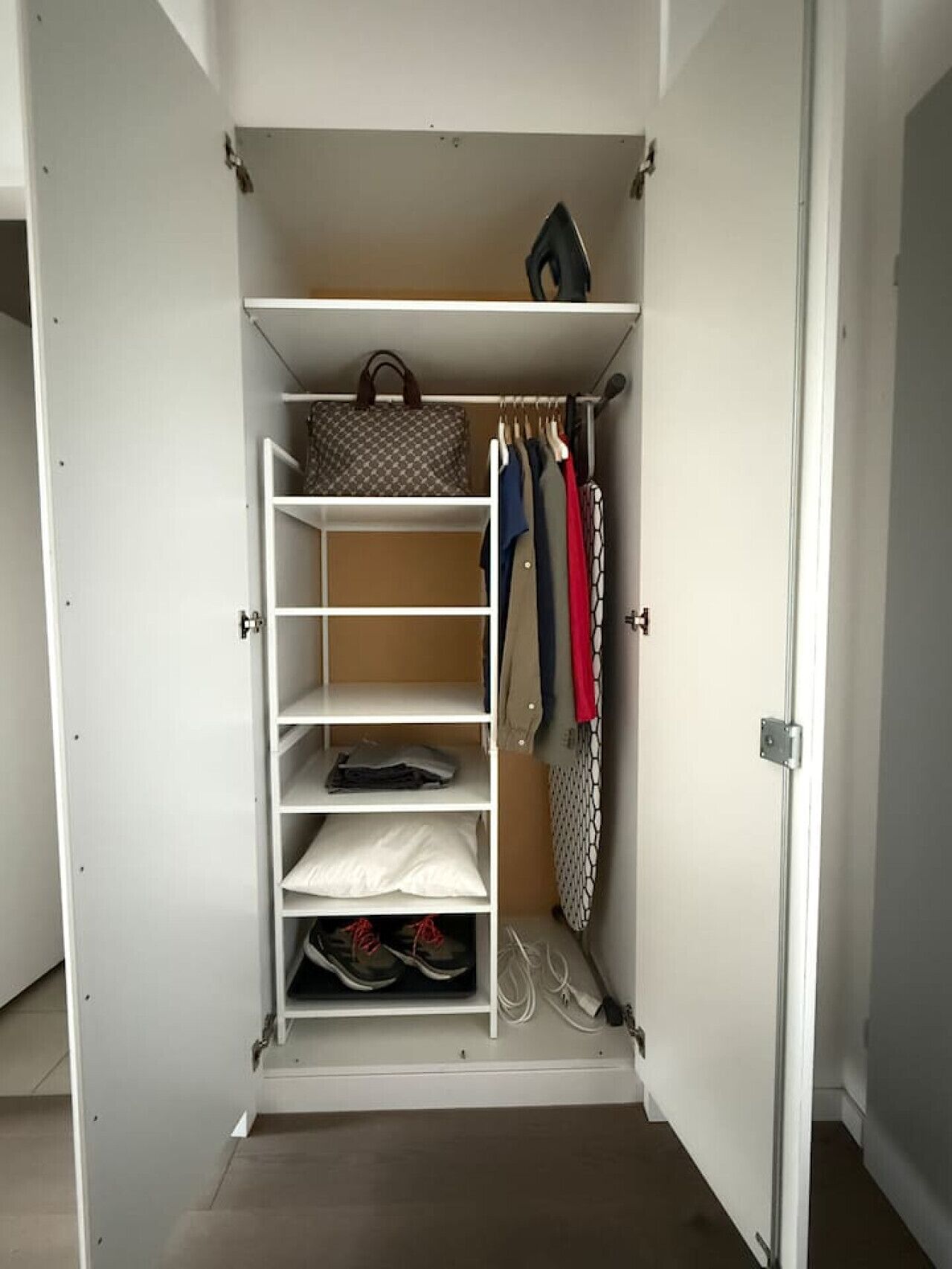 Un dressing avec de nombreuses étagères, un espace pour suspendre les vêtements et un porte-chaussures.