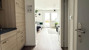 Une cuisine moderne avec des meubles en bois clair et un plan de travail noir, qui s’ouvre sur un coin repas comprenant une table et des chaises.