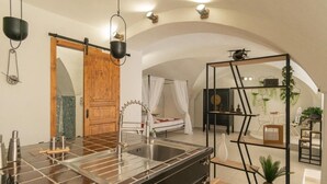 Een moderne keuken met een groot eiland, een losstaand spoelgedeelte en een bed met hemelbed op de achtergrond.