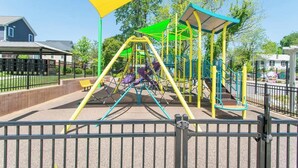 Ein Spielplatz mit einer gelben Markise, Schaukeln und einer Kletterkonstruktion.