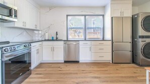 Eine moderne Küche mit weißen Schränken, Edelstahlgeräten und einem großen Fenster.
