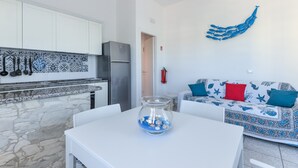 Una cucina moderna con mobili bianchi, un piano di lavoro in pietra e una ciotola di vetro su un tavolo bianco.