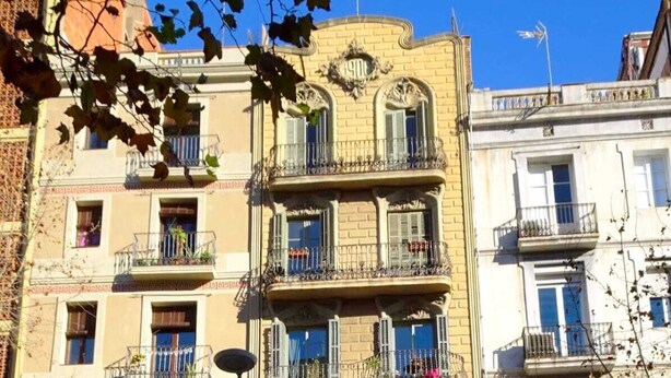 Um edifício com vários andares, varandas, uma loja no térreo e uma placa indicando limite de estacionamento de 4 horas.