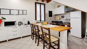 A kitchen with white cabinets, a wooden island, and a tiled backsplash. - Apartment 'Il Vagabondo' with Wi-Fi and Air Conditioning (Volta Mantovana)