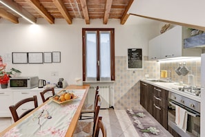 Una cucina con un tavolo da pranzo, sedie, un forno a microonde, un bollitore e un piano cottura.