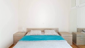 Une chambre à coucher comprenant un lit, deux tables de chevet, une commode et une armoire.