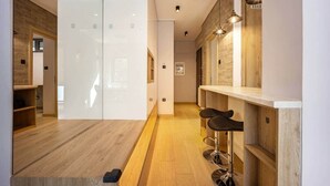 Een modern interieur met houten vloeren, een bar met krukken en hanglampen.