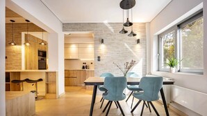 Een moderne keuken met houten kastjes, een eethoek met blauwe stoelen en een groot raam dat voor natuurlijk licht zorgt.