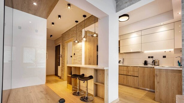Een moderne keuken met houten kastjes, een inbouwfornuis en een bar met krukken.