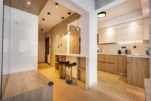 Une cuisine moderne avec des meubles en bois, une cuisinière encastrée et un coin bar avec des tabourets.