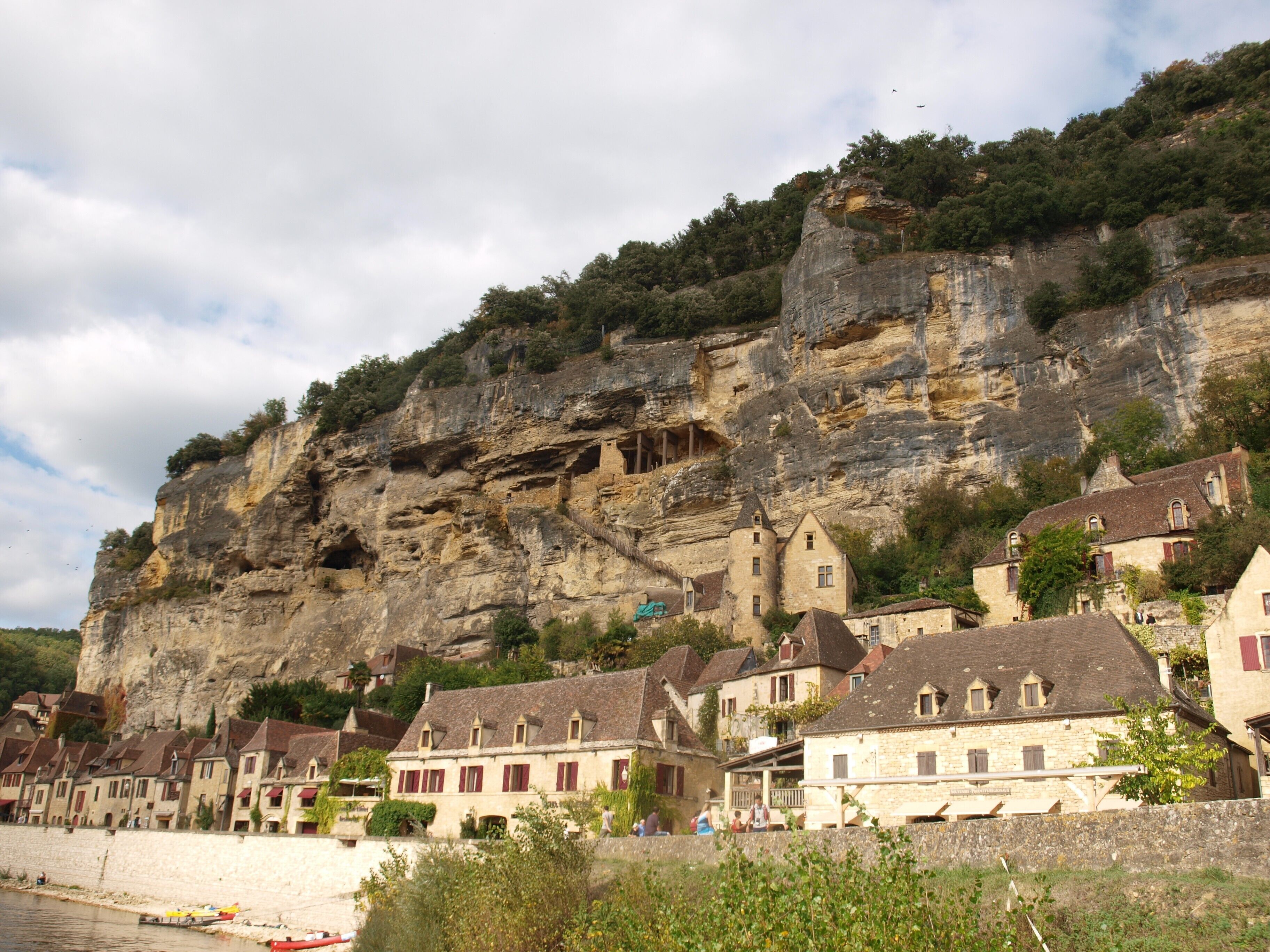 Ein Küstendorf mit Steinhäusern, einer Klippe und einem Strand.