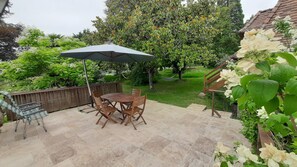 A patio with a table and chairs, a hammock, and a wooden fence. - L'hirondelle - la cipière gîtes (Peyzac-le-Moustier)