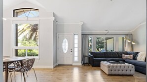 A spacious living area with a dark-colored sofa, a light-colored ottoman, and a dining table with chairs. - 3BR · Pool · Hot Tub · BBQ · Garage · Roseville (Roseville)