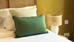 Un lit avec des oreillers blancs et verts, une tête de lit en bois et une lampe de chevet.