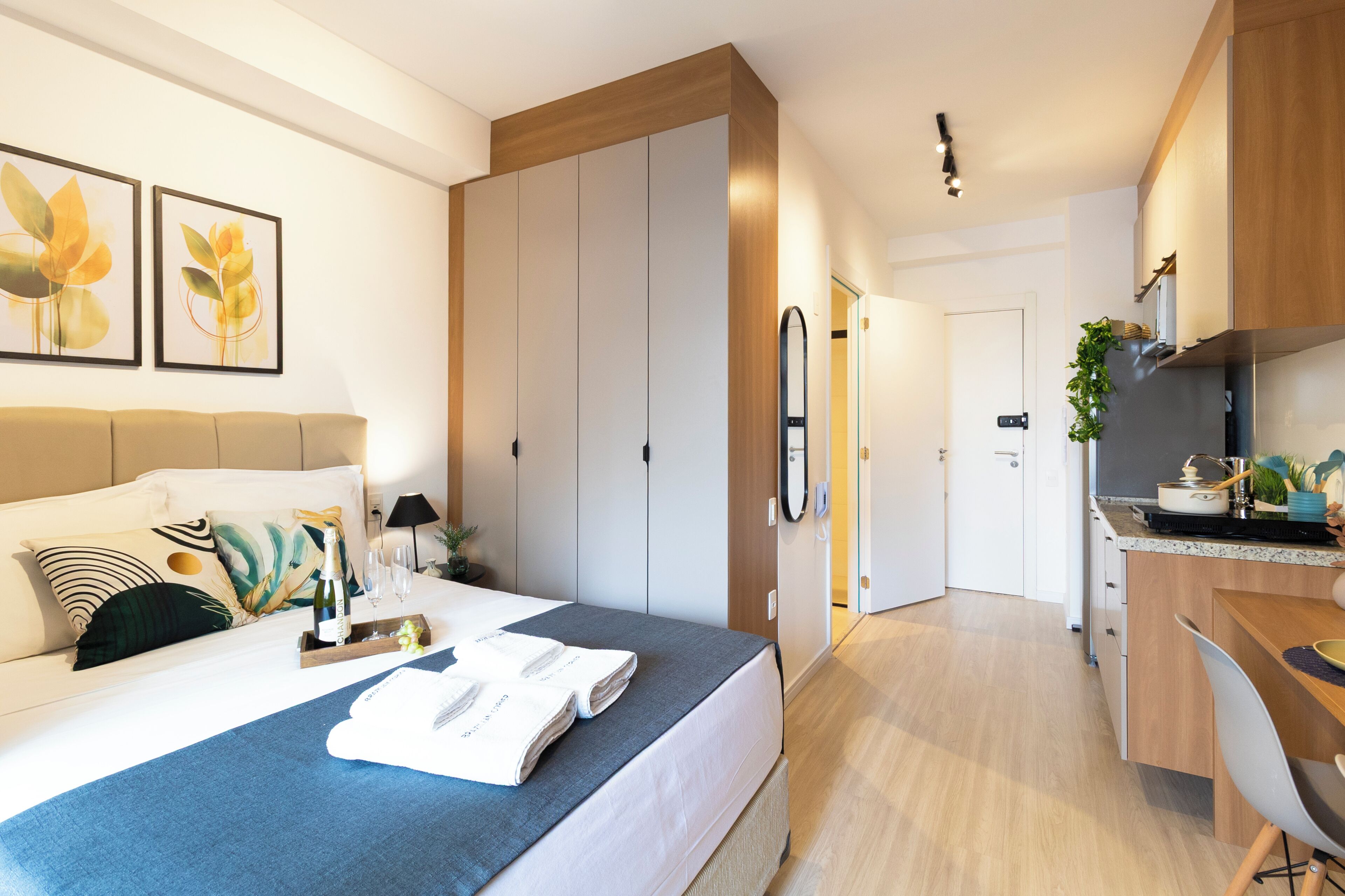 Una camera d'albergo moderna con un letto, un comodino, opere d'arte e un angolo cottura.