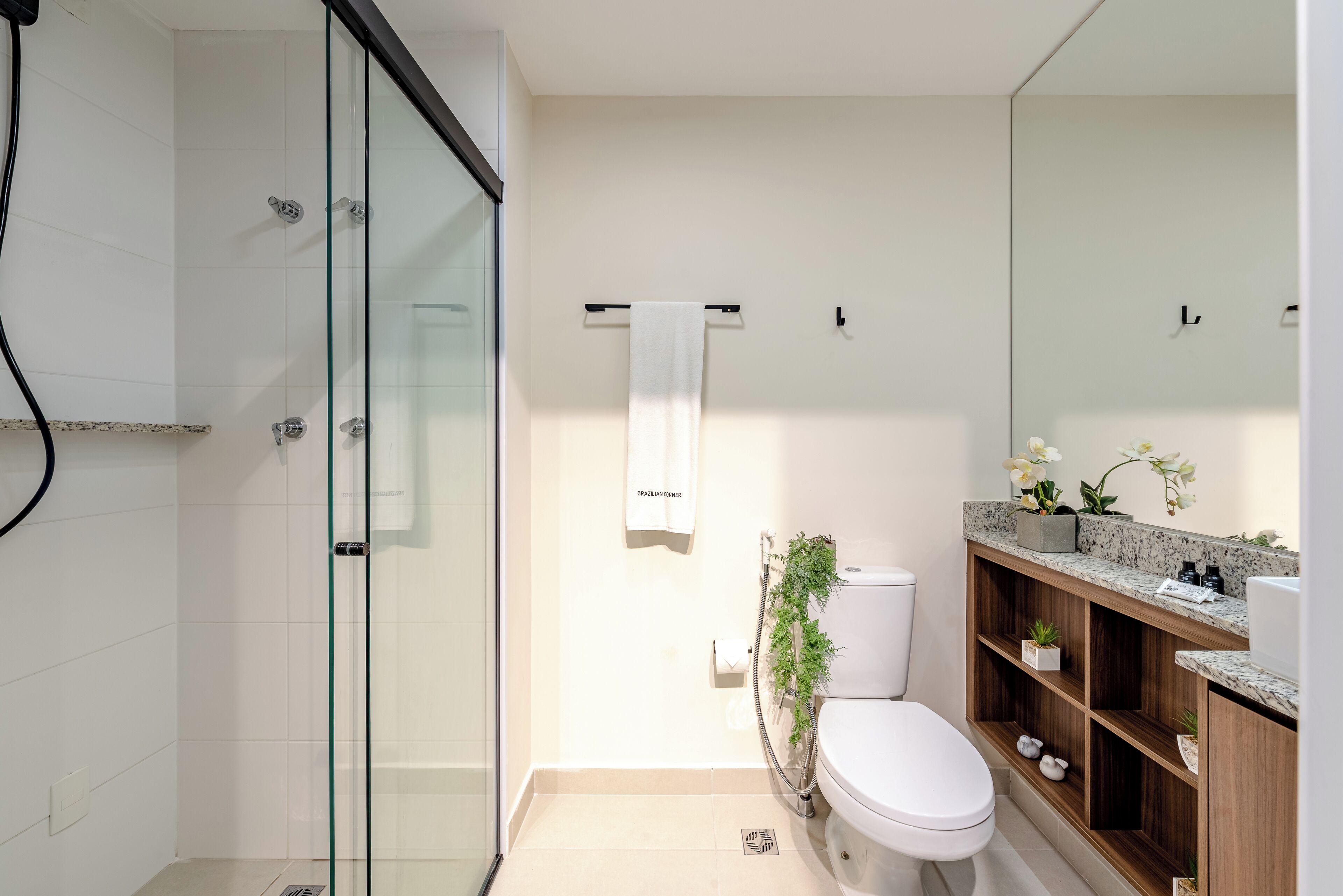 A modern bathroom with a glass shower enclosure, a toilet, and a vanity with a marble countertop.