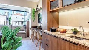 A modern kitchen with wooden cabinets, a granite countertop, and a built-in microwave. - Vila Mariana near Ibirapuera Park (São Paulo)