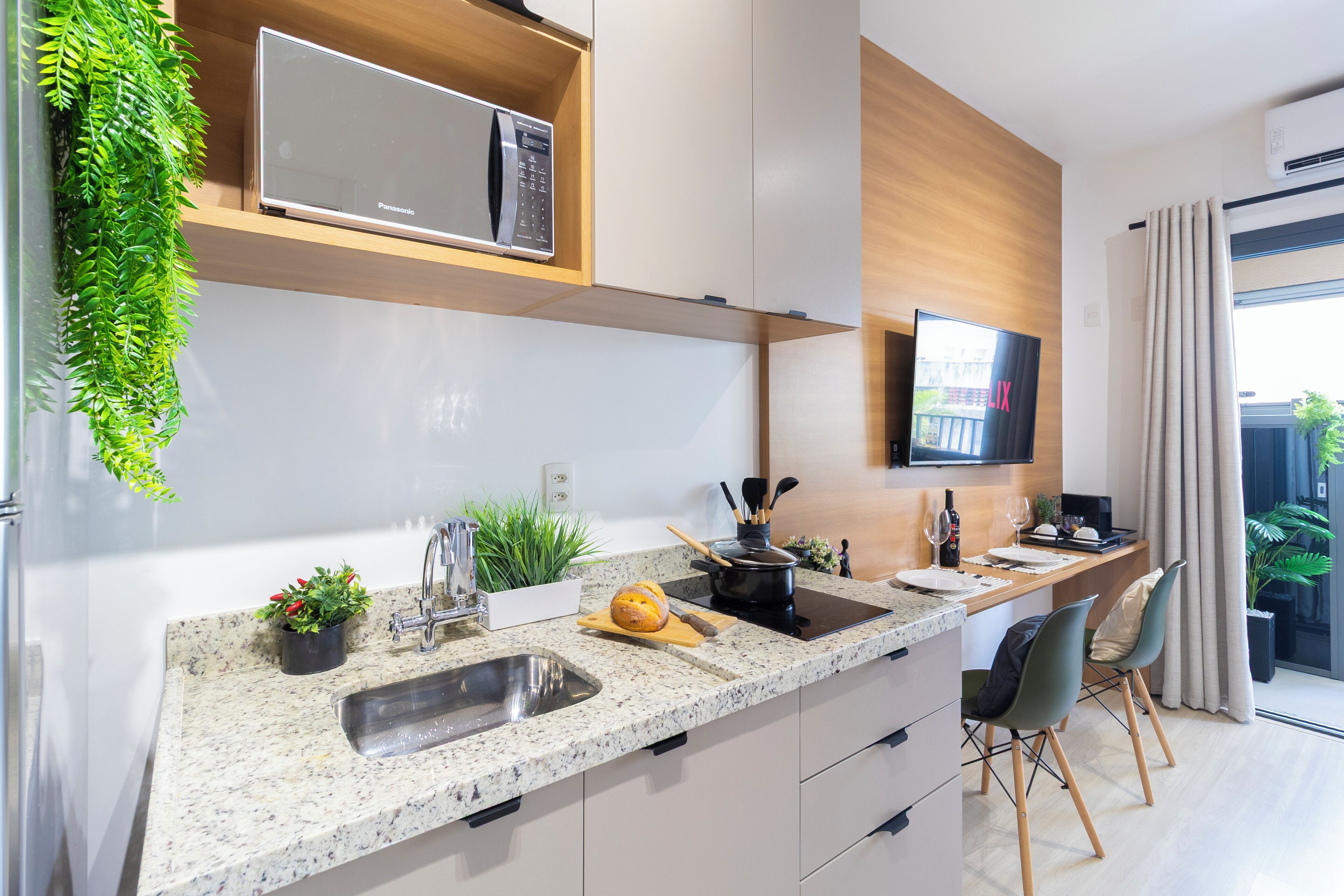 Una cocina moderna con microondas integrado, un lavamanos y una zona de comedor con sillas.