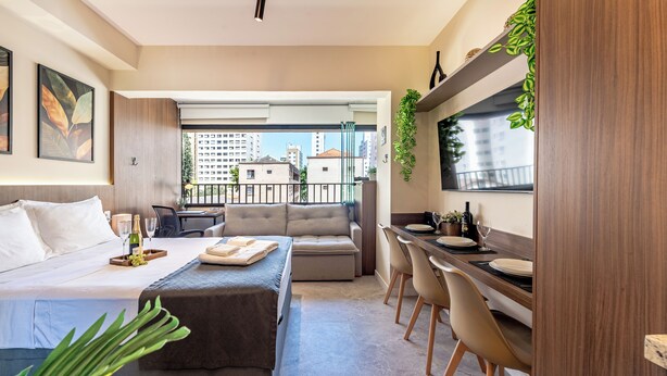 A modern hotel room with a bed, a sofa, a dining area, and a balcony with a city view. - Vila Mariana near Ibirapuera Park (São Paulo)