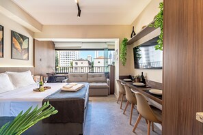 A modern hotel room with a bed, a sofa, a dining area, and a balcony with a city view. - Vila Mariana near Ibirapuera Park (São Paulo)