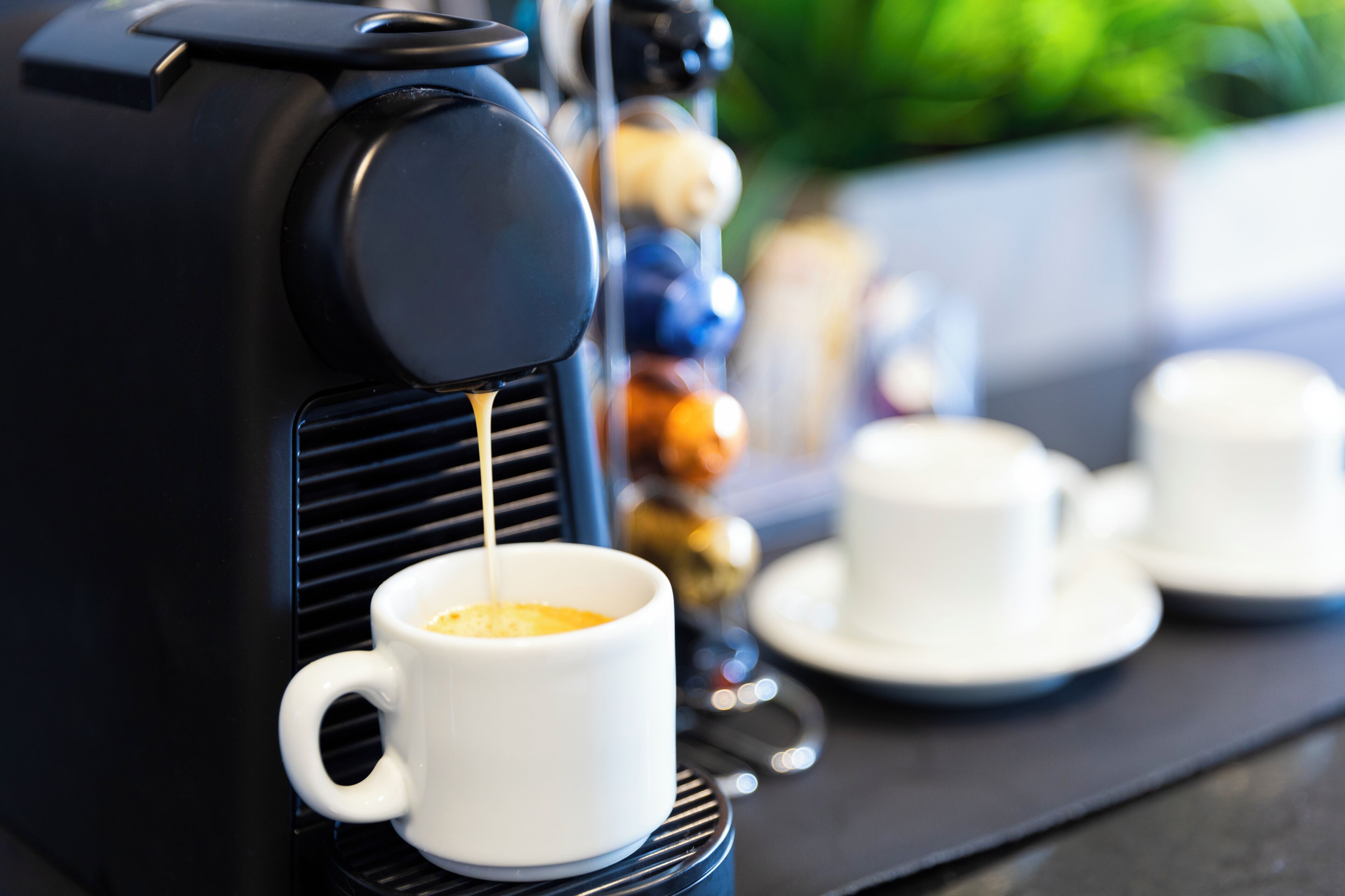 Uma máquina de café preparando um expresso em uma xícara branca.
