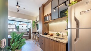 A modern kitchen with wooden cabinets, a stainless steel refrigerator, and a granite countertop. - Vila Mariana near Ibirapuera Park (São Paulo)