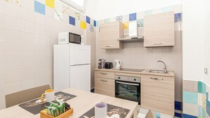 Una cocina compacta con microondas, horno y armarios de madera.