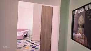 Un pasillo con una cama rosa, un cartel de San Giovanni y un suelo estampado.