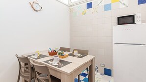 Una cocina pequeña con microondas, refrigerador y una mesa de comedor con sillas.